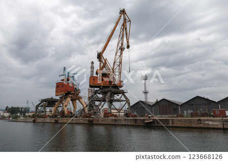 Industrial harbor scene featuring large cranes and warehouse buildings 123668126