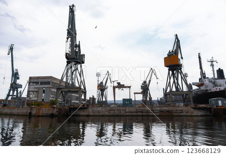 A busy industrial shipyard with large cranes, dockside buildings, and a ships 123668129