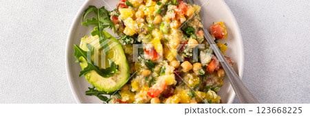 A vibrant vegetarian salad featuring boiled millet, chickpeas, fresh vegetables, and avocado, drizzled with olive oil for a delicious and healthy meal, banner 123668225