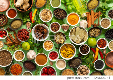 A vibrant assortment of fresh, multicolored spices and herbs on a delicate green background, perfect for cooking and culinary inspiration 123668281