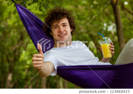 Young guy resting in a hammock in nature Young guy resting in a hammock in nature 123668425