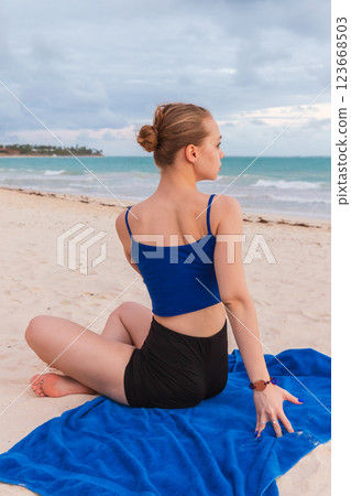 Young sporty blond girl does yoga, twist back stretching exercise 123668503