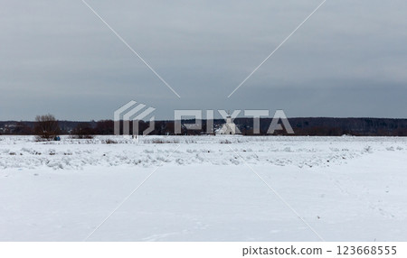 Expansive winter field covered in snow with a church in the distance Expansive winter field covered in snow with a church in the distance 123668555
