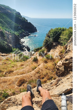 POV Person Sitting on Cliff Edge with Ocean View during Hiking Adventure in Gazipasa Turkey on Sunny POV Person Sitting on Cliff Edge with Ocean View during Hiking Adventure in Gazipasa Turkey on Sunny 123668832
