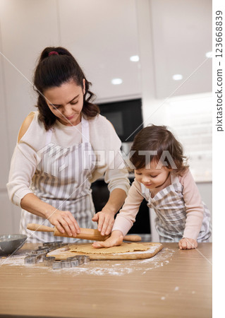 Happy mother and cute little child daughter rolling dough for homemade pastry. 123668839