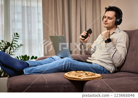 freelancer man using smart phone and laptop on sofa at home 123668846
