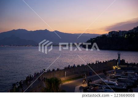 Antalya waterfront at sunset with people, boats, and mountain silhouette view Antalya waterfront at sunset with people, boats, and mountain silhouette view 123669008