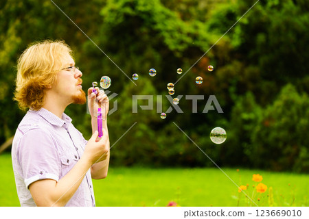Man blowing soap bubbles outdoor 123669010