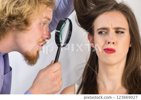 Man looking at woman hair through magnifer 123669027
