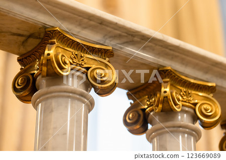 Golden floral capital accents on white marble columns 123669089