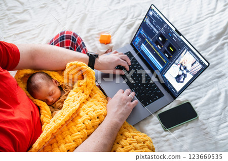 Man multitasking with laptop and baby on bed 123669535
