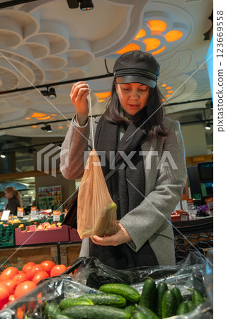 Woman Shopping for Cucumbers with Reusable Bag 123669558