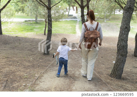 Mother and son walking on dirt path in forest 123669595