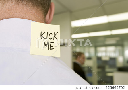 April Fools Day prank with kick me note on man back in plaid jacket, city street or office background 123669702