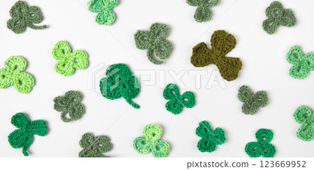 St Patrick's Day concept. Composition made of knitted green shamrocks on a gray background. Holiday sign and knitted clover leaf. Copy space, flat lay, place for text 123669952