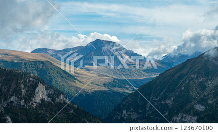 A panoramic view of a mountain range with a valley below. The mountains are covered in green vegetation and the valley is filled with lush forests. Clouds cover the peaks of the mountains A panoramic view of a mountain range with a valley below. The mountains are covered in green vegetation and the valley is filled with lush forests. Clouds cover the peaks of the mountains 123670100