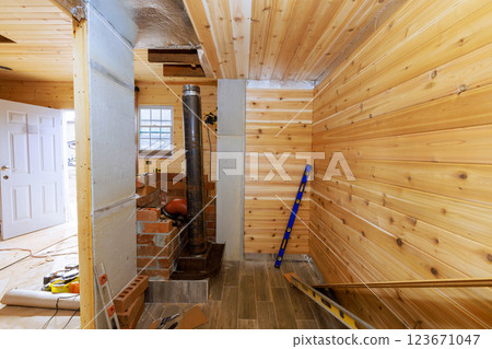 Renovation work in wooden sauna cabin interior with new paneling stove installation, creating warm atmosphere 123671047