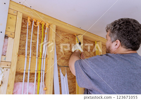 Worker applies foam insulation prepares electrical wiring in home renovation on improving energy efficiency. 123671055