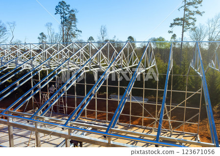 Workers construct steel framed structure surrounded by new metal warehouse it steel beams 123671056
