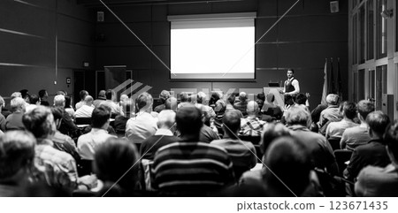 Speaker giving a talk in conference hall at business meeting event. Rear view of unrecognizable people in audience at the conference hall. Business and entrepreneurship concept. Speaker giving a talk in conference hall at business meeting event. Rear view of unrecognizable people in audience at the conference hall. Business and entrepreneurship concept. 123671435