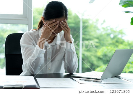 A businesswoman sits with her hands covering her face to show that she is bored 123671805
