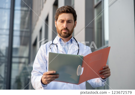 Determined male doctor in a lab coat with a prescription list in hands 123672579