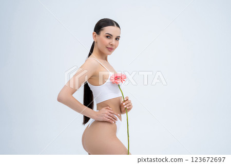 Pretty long-haired young woman in white lingerie with a pink flower in hands 123672697