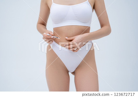 Close up of a young woman making injection into her belly Close up of a young woman making injection into her belly 123672717