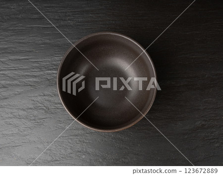 Empty bowl on black tabletop, dark porcelain plate, moody dish mockup, kitchen banner 123672889