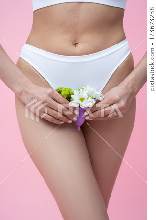 Female wearing absorbent underwear representing menstrual health care holding floral menstrual cup 123673238