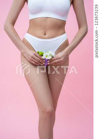 Unrecognizable woman holding menstrual eco-friendly reusable silicone cup with flowers Unrecognizable woman holding menstrual eco-friendly reusable silicone cup with flowers 123673239