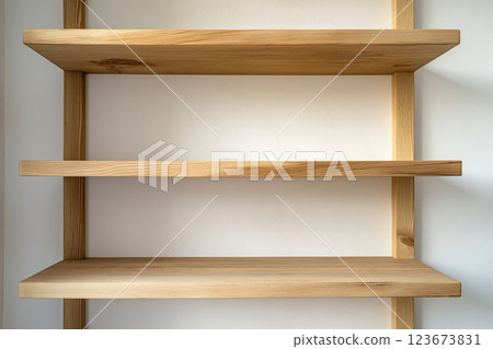 Closeup photo showcasing a simple, elegant wooden wall shelf against a soft, neutral backdrop, providing a clean, functional aesthetic 123673831