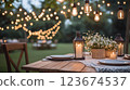Romantic dinner table setting outdoors with hanging lights and lanterns 123674537
