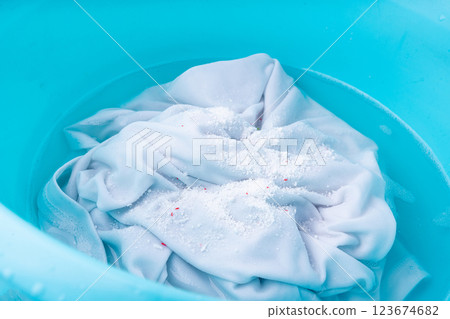 Hand laundry washing clothes in blue plastic basin with detergent powder and oxygen bleach 123674682