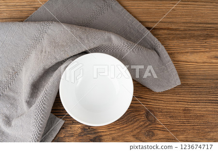 Empty white bowl on table, porcelain plate on wooden tabletop and grey tablecloth, minimal Empty white bowl on table, porcelain plate on wooden tabletop and grey tablecloth, minimal 123674717