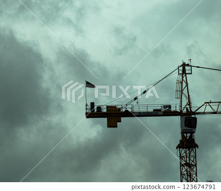 Portland, Oregon, USA - 10.25.2023: US flag on a construction crane in cloudy weather. Portland, Oregon, USA - 10.25.2023: US flag on a construction crane in cloudy weather. 123674791