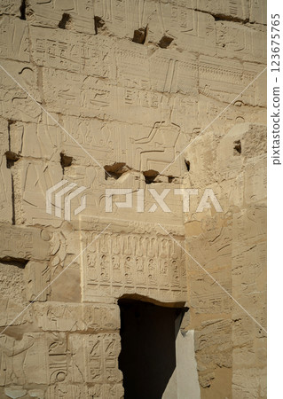 Egyptian ancient wall with carved hieroglyphs and door to temple 123675765