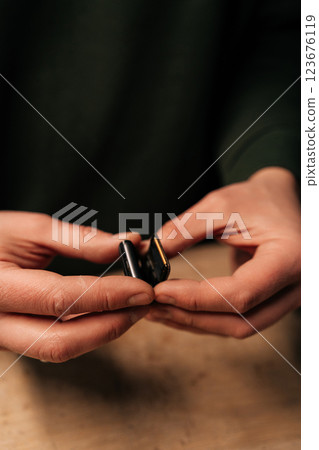 High-angle view of unrecognizable repairman preparation to replacement smartwatch battery, showing precision workmanship during delicate electronic maintenance process. Concept of repairing, upgrade. High-angle view of unrecognizable repairman preparation to replacement smartwatch battery, showing precision workmanship during delicate electronic maintenance process. Concept of repairing, upgrade. 123676119