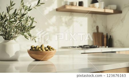 A traditional kitchen with a bowl of olives and an olive branch on the countertop.  123676163
