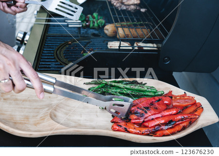 Delicious grilled vegetables asparagus, paprika on barbecue grill with smoke and flame. Asparagus and red paprika on the wooden plate. 123676230