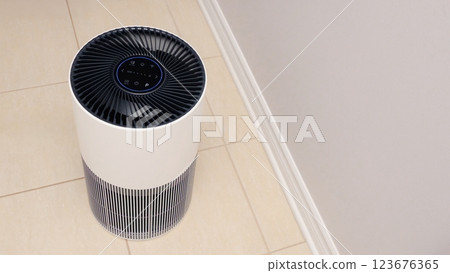 Sleek Modern Tall Air Purifier with Black Fan on Beige Tile Floor in Stylish Room Sleek Modern Tall Air Purifier with Black Fan on Beige Tile Floor in Stylish Room 123676365