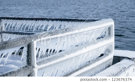 Beautiful Icicles Hanging from a Metal Railing Overlooking a Stunning Frozen Lake Scene Beautiful Icicles Hanging from a Metal Railing Overlooking a Stunning Frozen Lake Scene 123676374