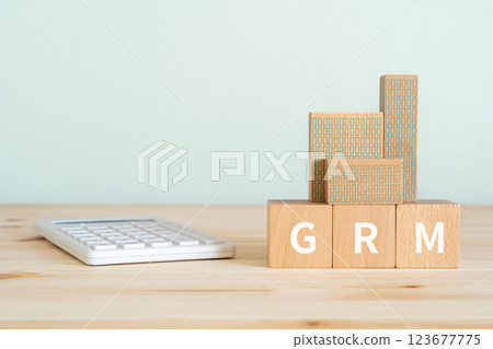 一塊寫著 GRM 的木塊、一台計算器和一處房地產模型 123677775