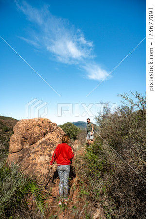 Two young adults hiking on rocky trail in sunny mountain landscape Two young adults hiking on rocky trail in sunny mountain landscape 123677891
