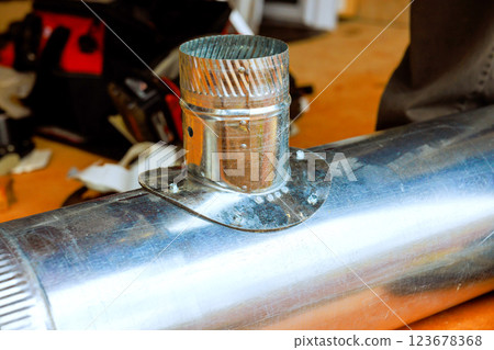 Contractor attaches metal pipe connector to larger pipe, during renovation works HVAC heating duct at construction site Contractor attaches metal pipe connector to larger pipe, during renovation works HVAC heating duct at construction site 123678368