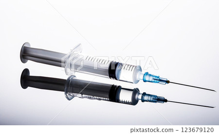 syringe, A medical syringe with a needle, filled with liquid, placed on a reflective surface with a white background syringe, A medical syringe with a needle, filled with liquid, placed on a reflective surface with a white background 123679120