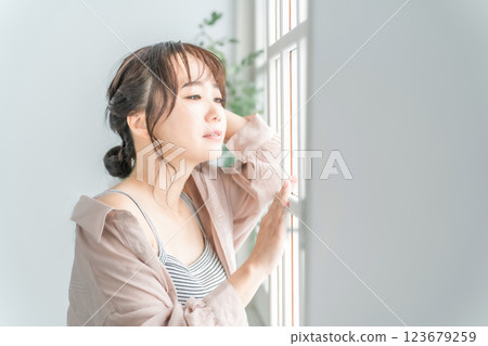 Beauty image of an Asian woman standing by the window in the morning (sunbathing, skin care, ultraviolet rays) 123679259