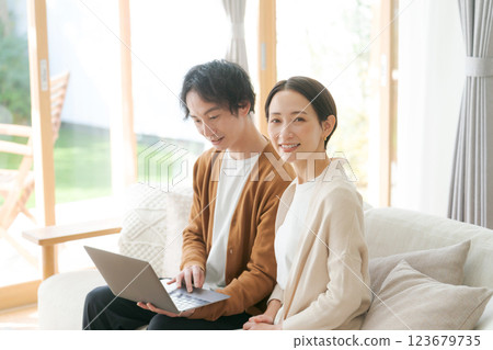 A couple sitting on a sofa looking at a computer 123679735