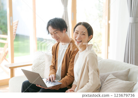 A couple sitting on a sofa looking at a computer 123679736