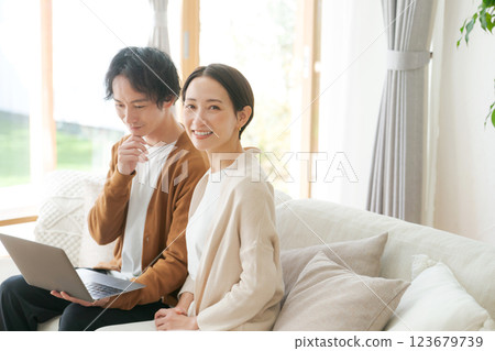 一對夫婦坐在沙發上看電腦 一對夫婦坐在沙發上看電腦 123679739